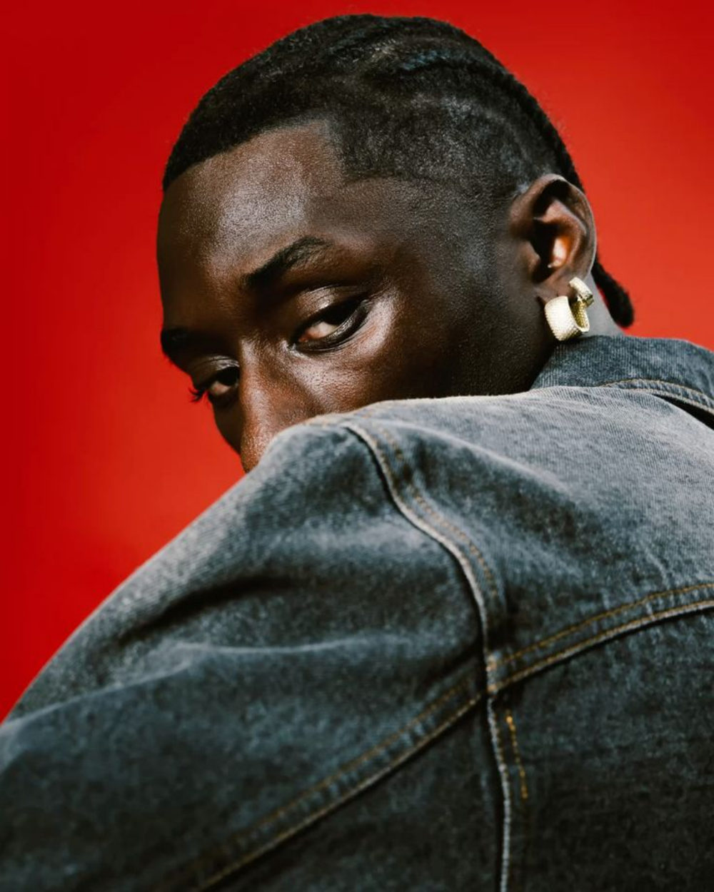 Retrato de espaldas con campera de jean sobre fondo rojo